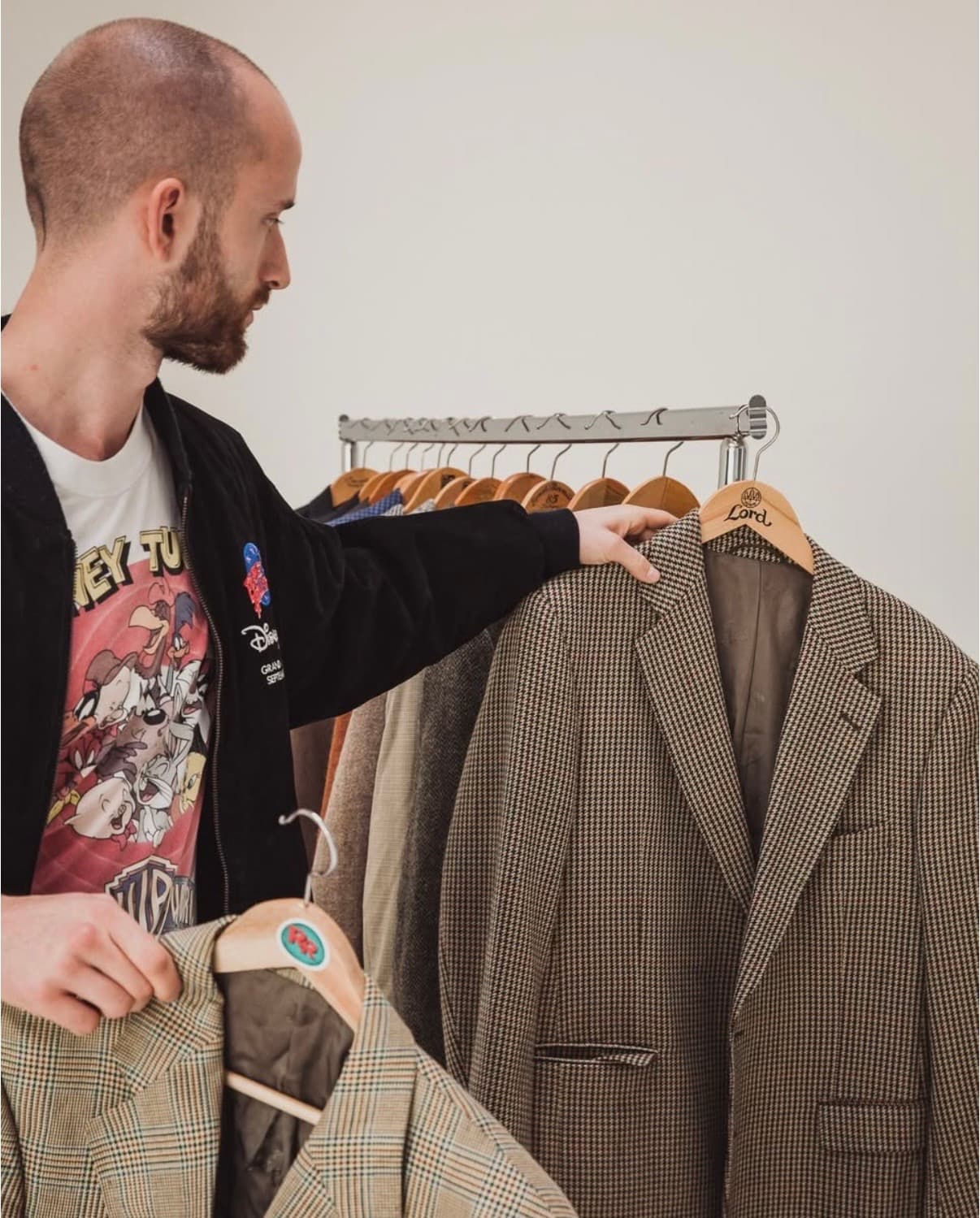 Max, Gründer von RareRags, beim Sortieren einer Kleidungsstange mit Blazern.